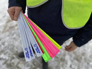Policjant trzymający w dłoni opaski odblaskowe