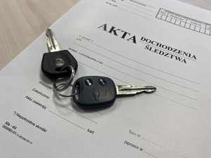 Kluczyki do samochodu leżące na okładce akt dochodzenia/ śledztwa.