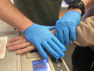 Zatrzymanemu policjant pobiera odciski palców.