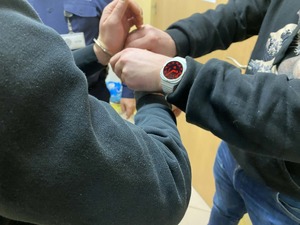 Policjant kryminalny zdejmuje zatrzymanemu mężczyźnie kajdanki