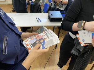 Policjantka rozdaje ulotki informacyjne