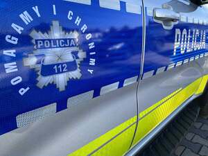 Drzwi policyjnego radiowozu. Napis: Pomagamy i Chronimy