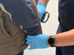 Policjant zakłada zatrzymanemu kajdanki