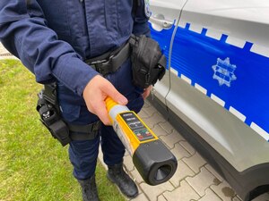 Policjantka przy radiowozie z alkomatem w dłoni