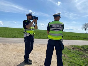 Policjanci przy drodze za pomocą ręcznego miernika prędkości kontrolują prędkość pojazdów