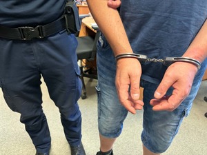 Policjant prowadzi zatrzymanego mężczyznę